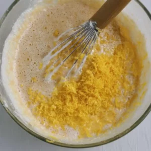 Lemon zest being mixed into light cake batter for a homemade sugar-free lemon blueberry pudding cake.