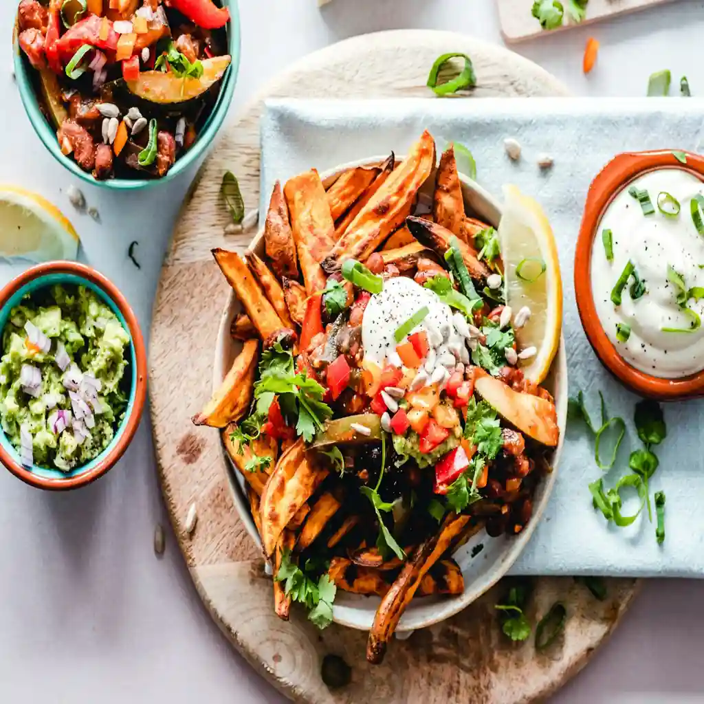 Healthy balanced plate with roasted vegetables, protein, avocado dip, and nutritious side dishes.