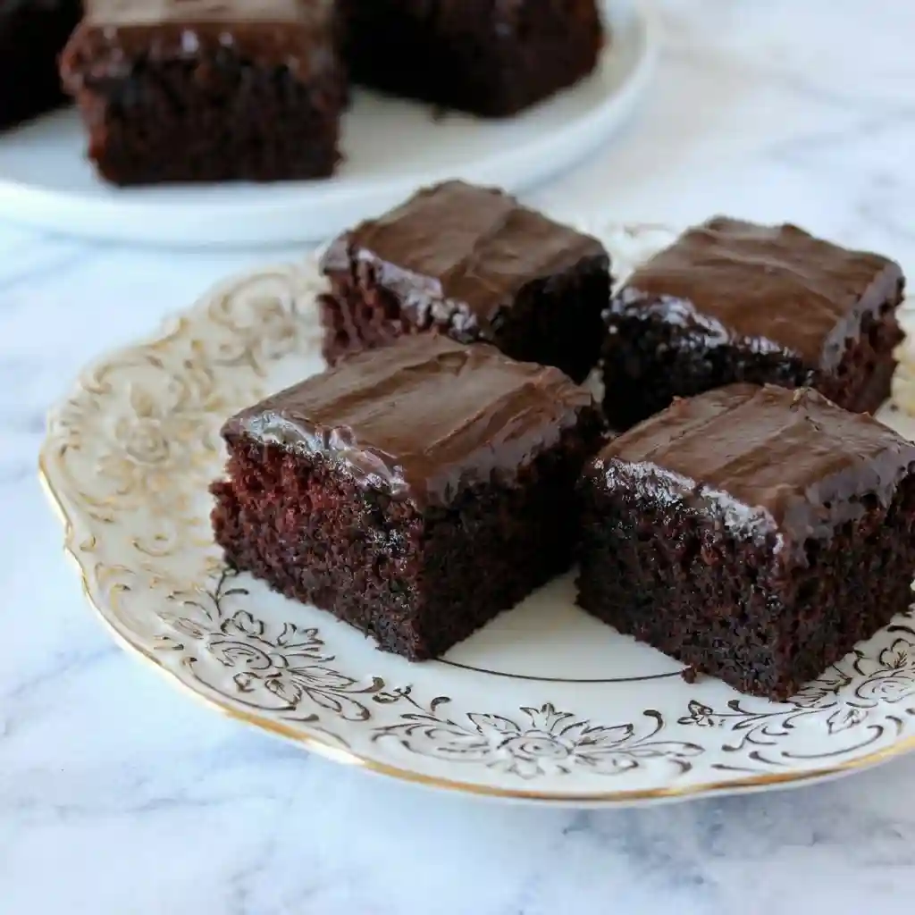 Moist one-bowl chocolate cake with glossy chocolate frosting on a decorative plate